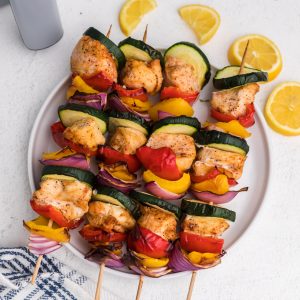 chicken kabobs made in the air fryer with lemon slices and served on a white plate.