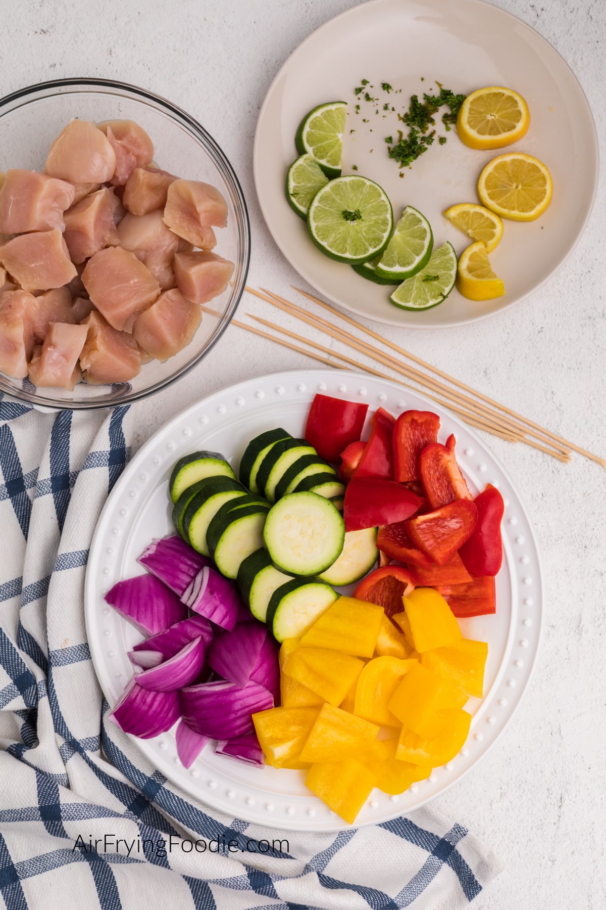 Chopped vegetables on a plate. wooden skewers, chicken bites, and lime and lemons and a plate.