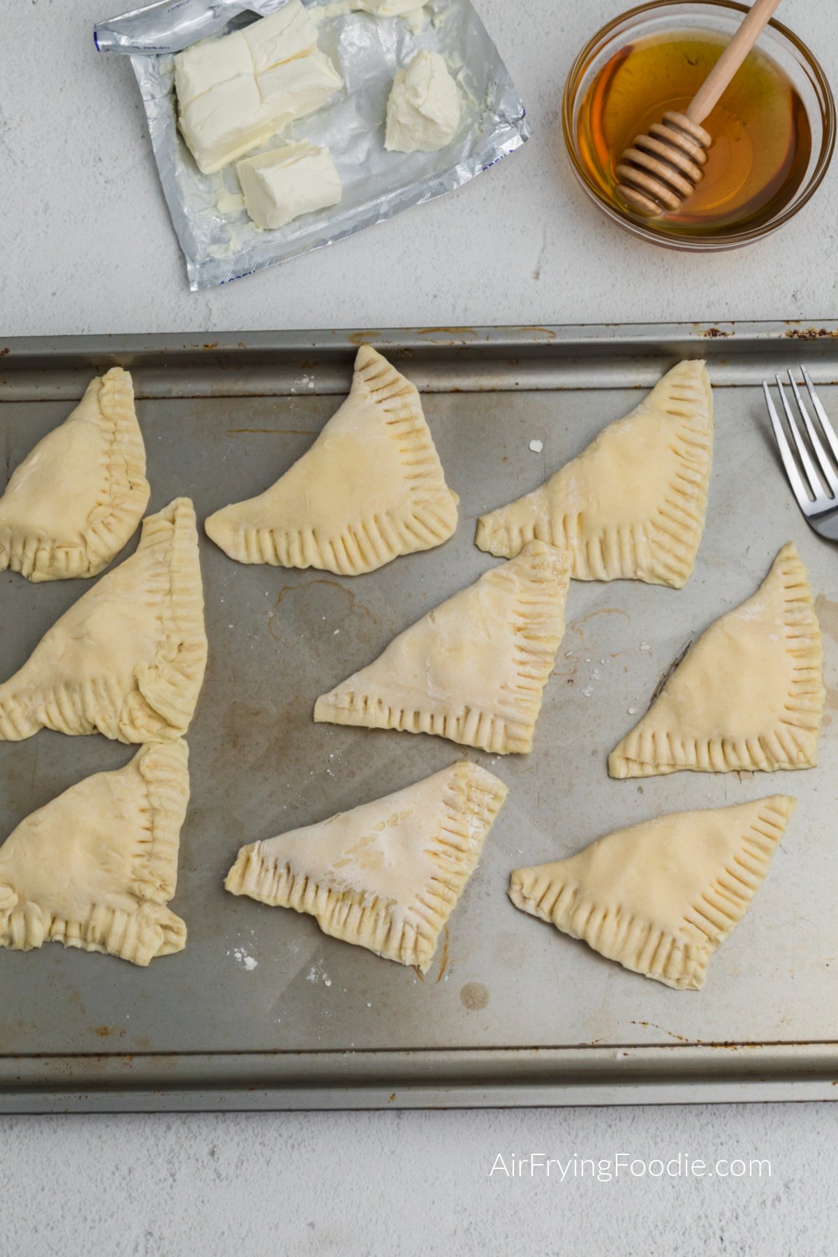 Cream cheese puff pastry folded over and pinched with a fork, ready to air fry.