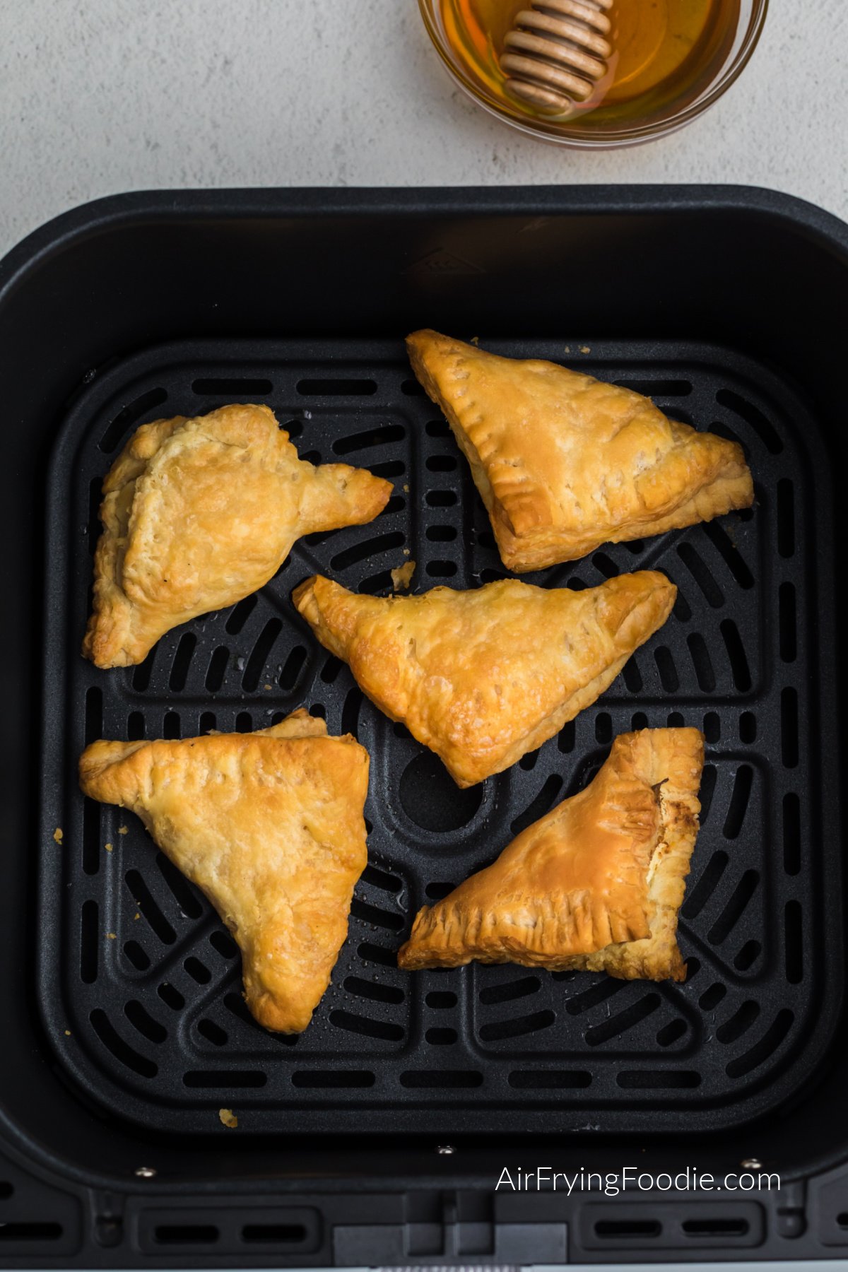 Air fried cream cheese puff pastry in the air fryer basket.