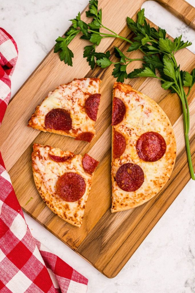 Golden crispy pepperoni pizza cut into slices on a wooden cutting board