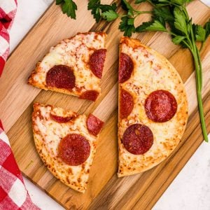 Golden crispy pepperoni pizza on a wooden cutting board