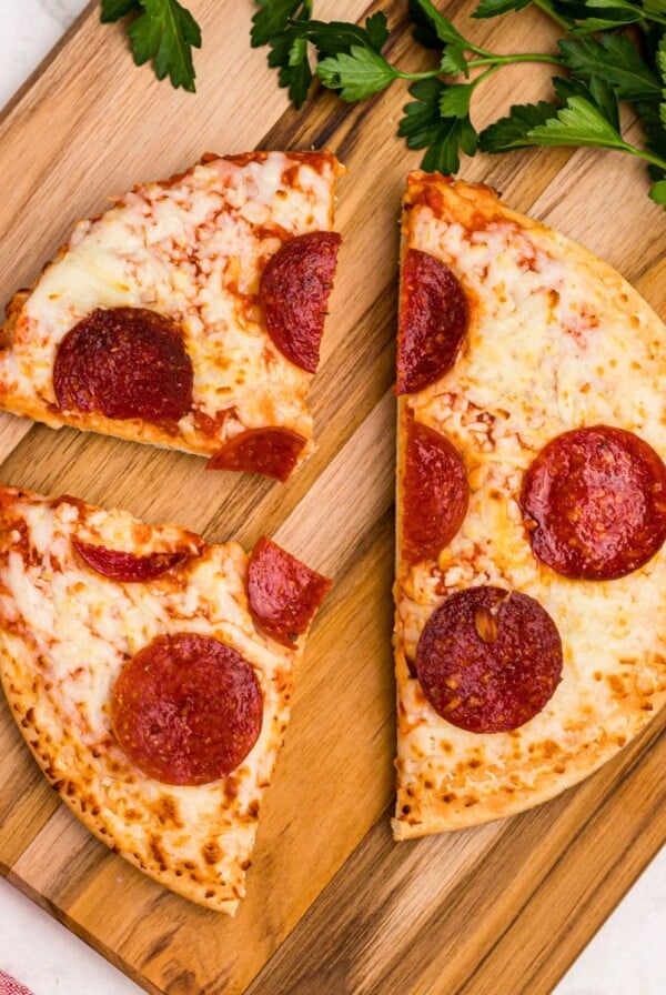 Golden crispy pepperoni pizza on a wooden cutting board