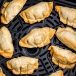 Golden crispy potstickers in the air fryer basket after being cooked.