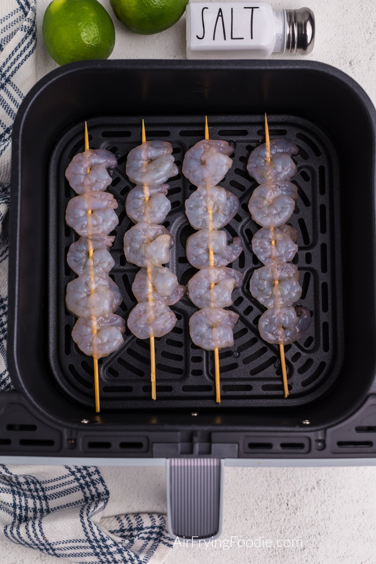 fresh shrimp on skewers in a single layer in the air fryer basket.