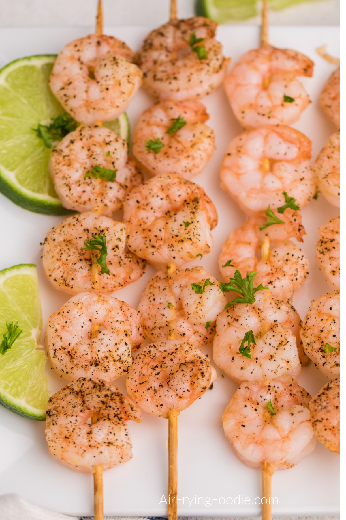 Shrimp skewers made in the air fryer and served on a white plate.