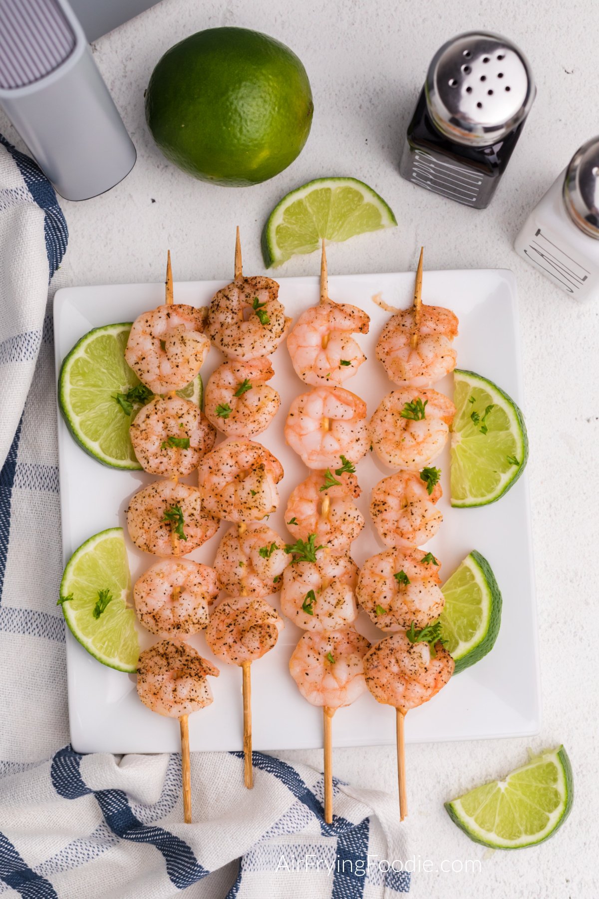 Shrimp skewers made in the air fryer and served with slices of lime.