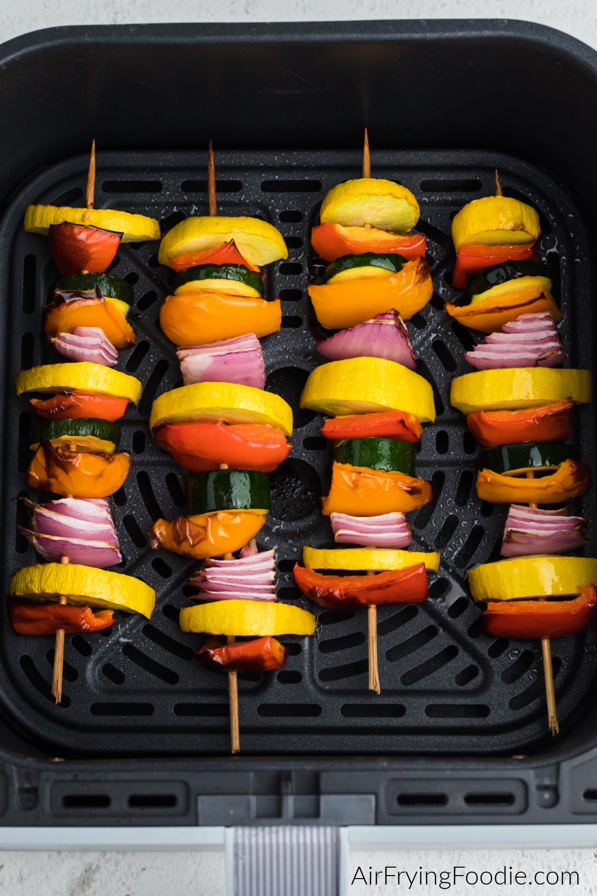 Air fried vegetable kabobs in a single layer in the basket of the air fryer.
