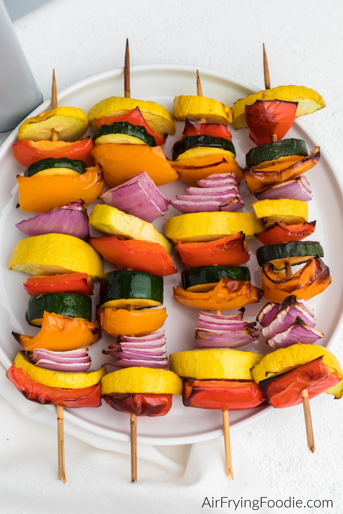 Air fried vegetable kabobs served on a white plate.