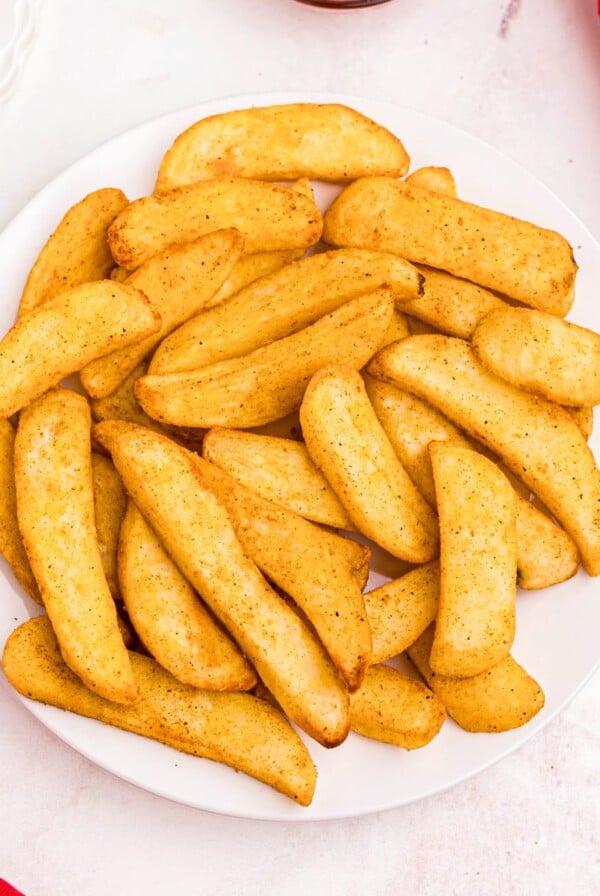 Seasoned Red Robin steak fries on a white plate with a small bowl of ketchup.