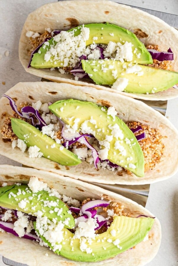 Battered cooked fish pieces in a flour tortilla tipped with avocado, cabbage and cheese.