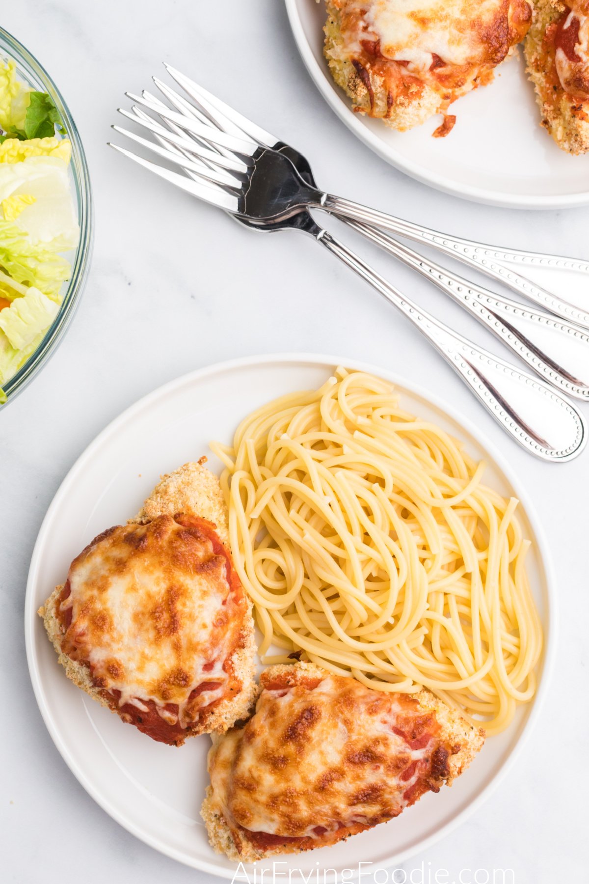 Overhead photo of chicken parmesan made in air fryer on a plate with spaghetti noodles.