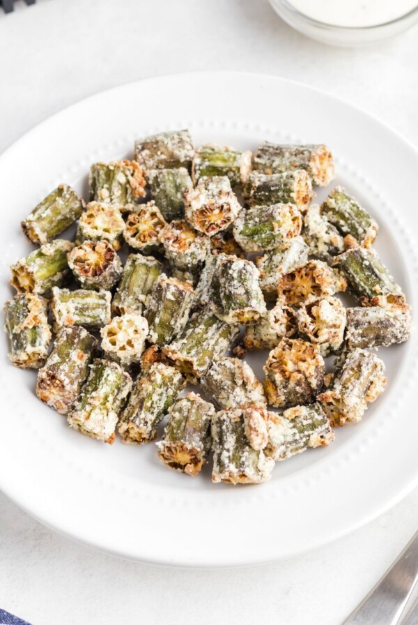 Golden fried seasoned okra pieces in a white plate.