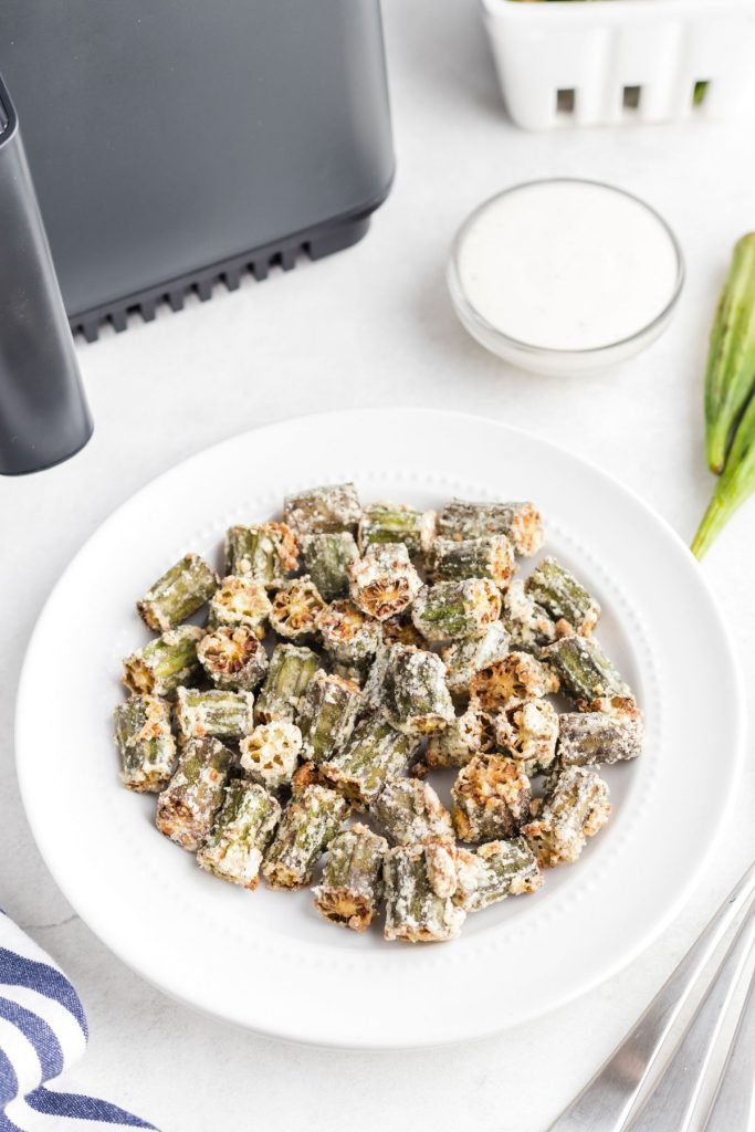 Golden fried seasoned okra pieces in a white plate.