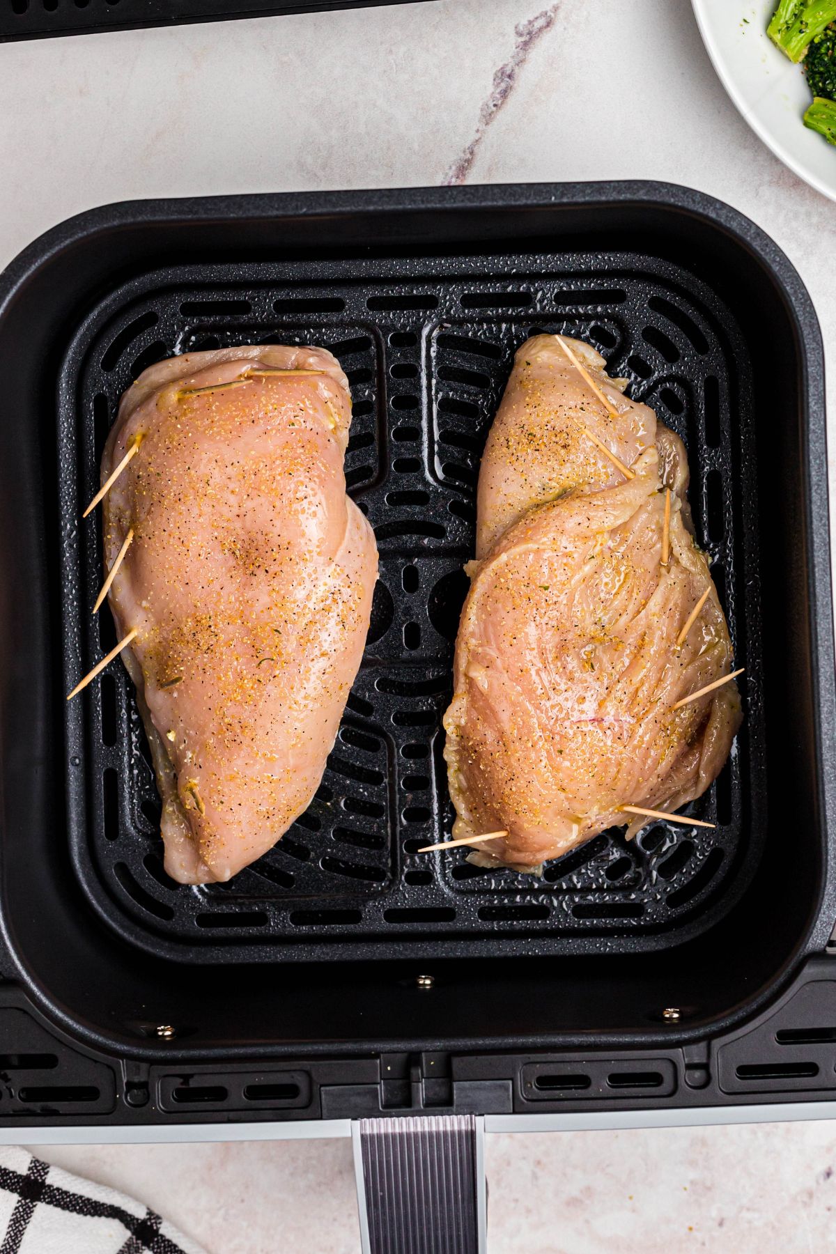 Uncooked stuffed chicken in the air fryer basket.