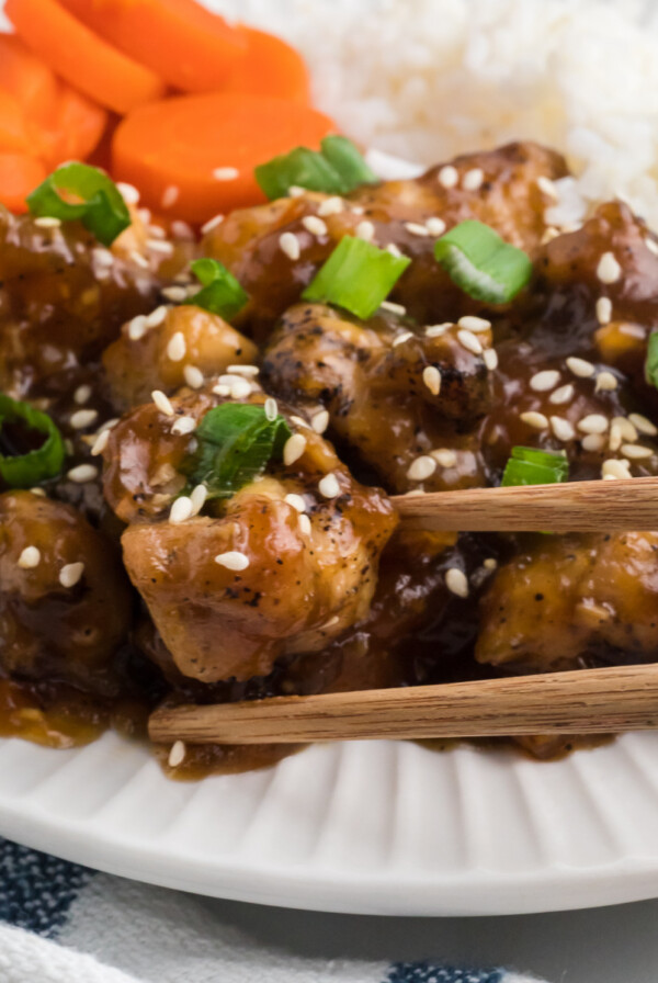 Air fryer teriyaki chicken on a plate with a side of rice and sliced carrots.