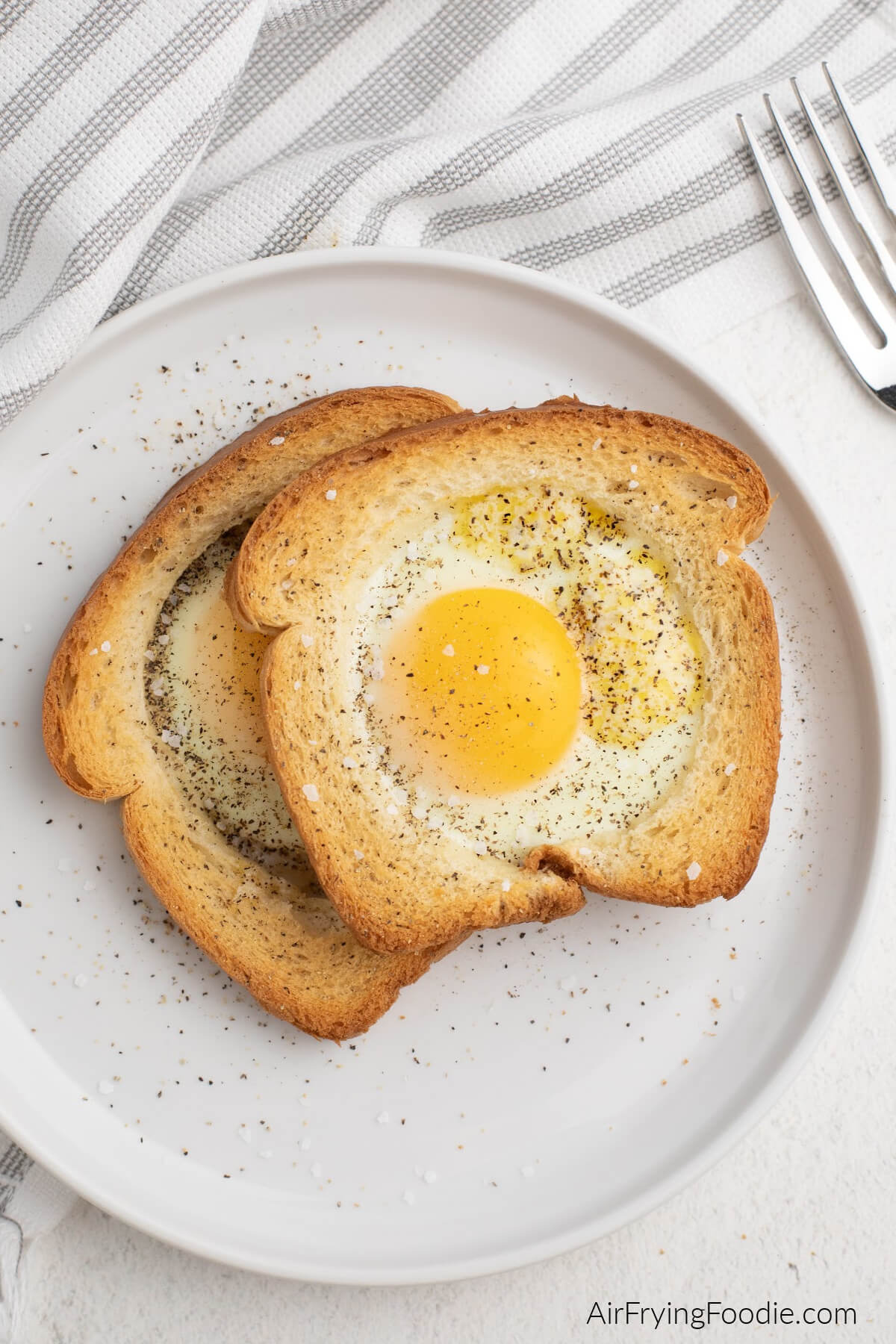 Air fryer eggs in a basket, seasoned with salt and pepper and ready to serve. On a white plate. 