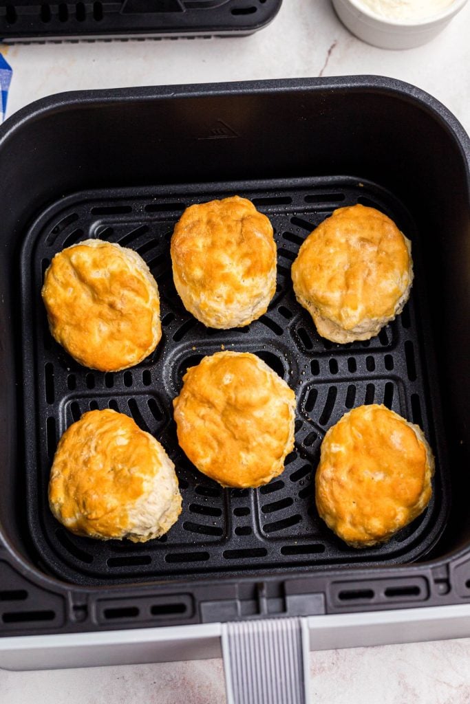 Golden biscuits in the air fryer basket after being cooked. 