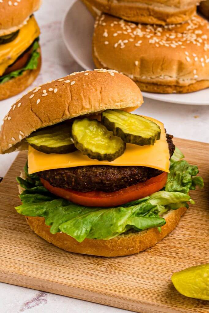 Juicy burger patty on bun with lettuce tomato, and pickles.