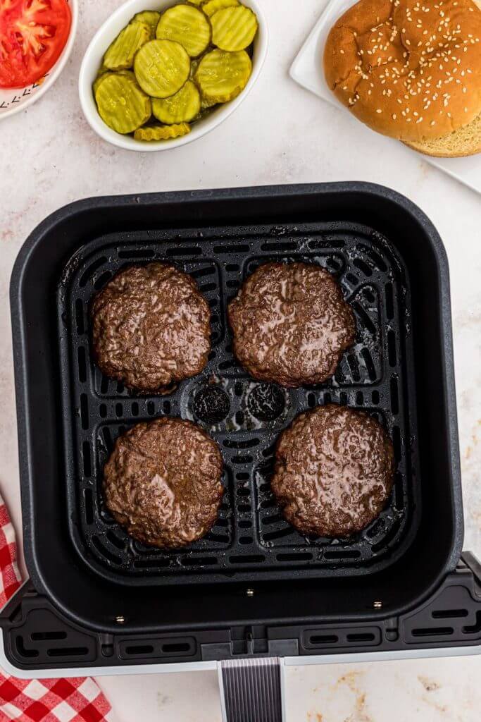 Four juicy hamburger patties cooked in the air fryer basket. 