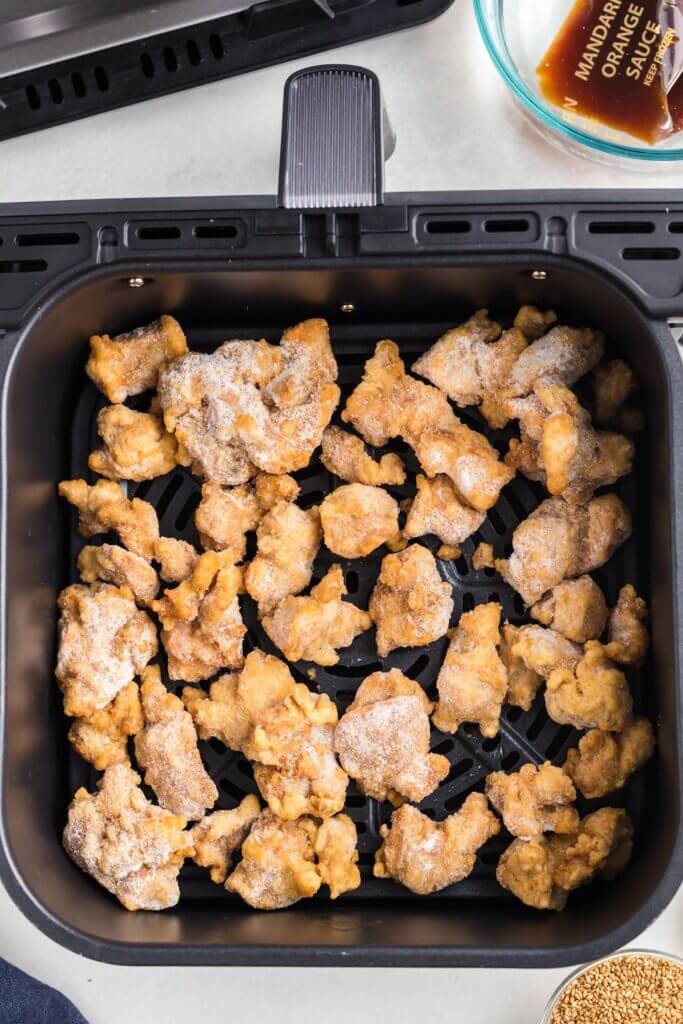 Frozen pieces of breaded chicken in the air fryer basket before being cooked. 