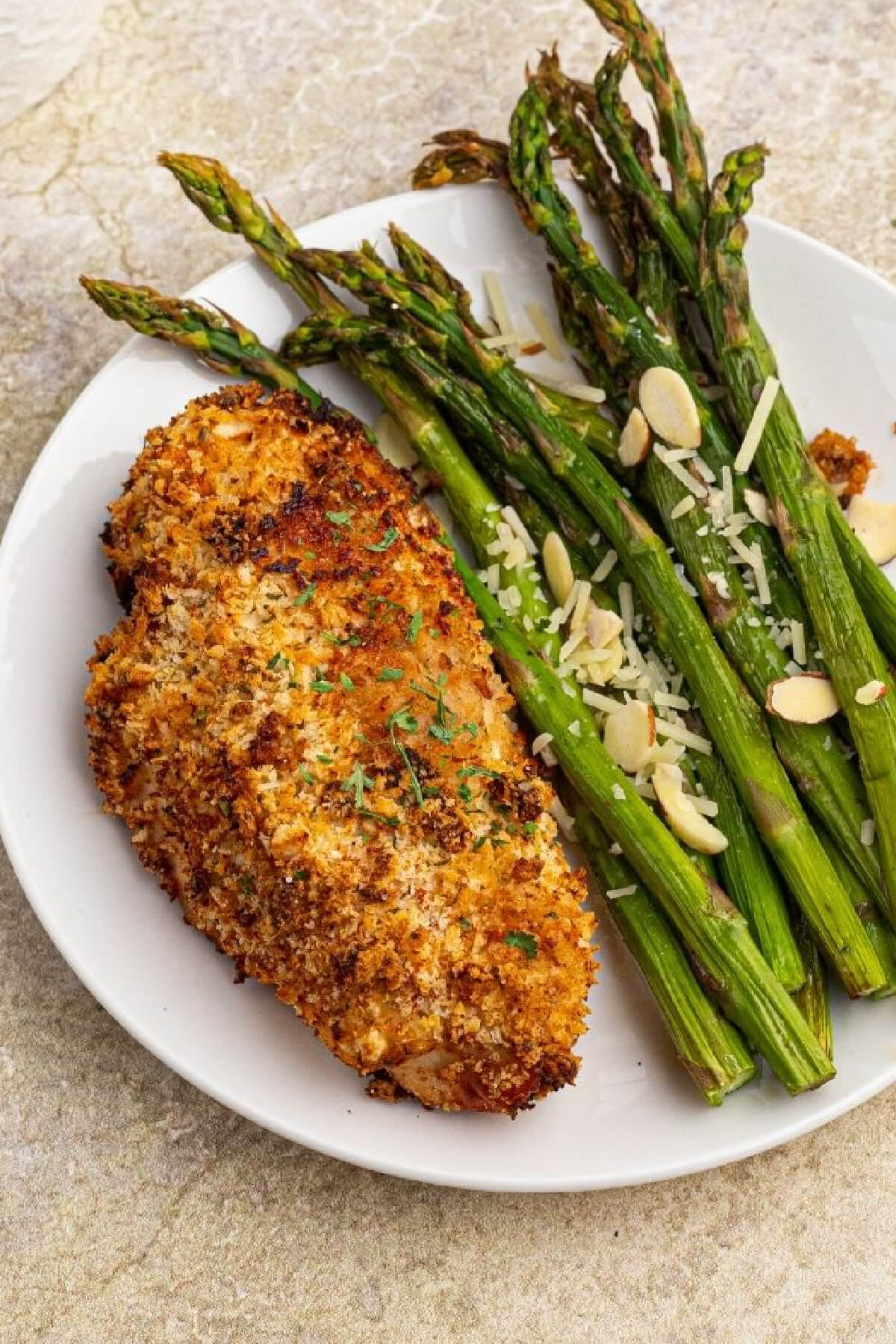air fryer parmesan crusted chicken on a plate with asparagus.
