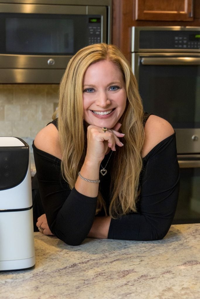 Photo of Becky in a black shirt in the kitchen next to the air fryer.