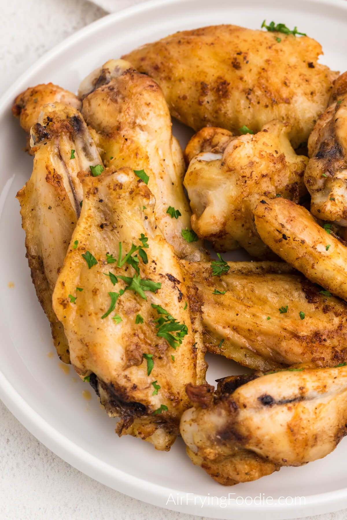 Chicken wings on a white plate that were cooked from frozen using the air fryer. 