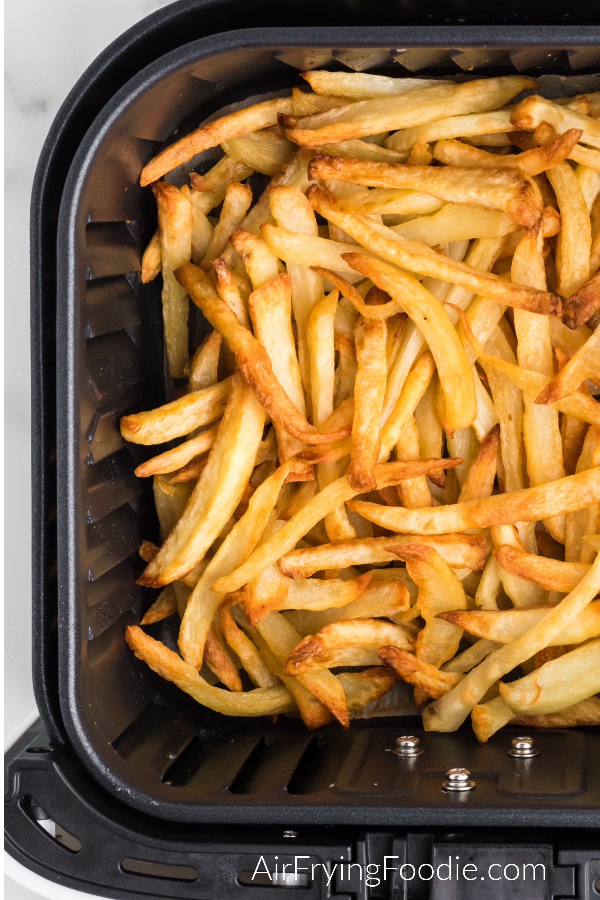 Close up of reheated fries in air fryer basket. 