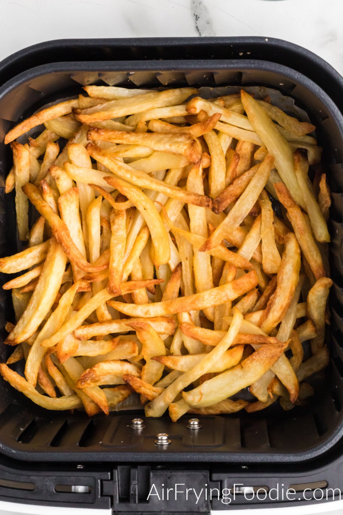 Reheated fries in the basket of the air fryer.