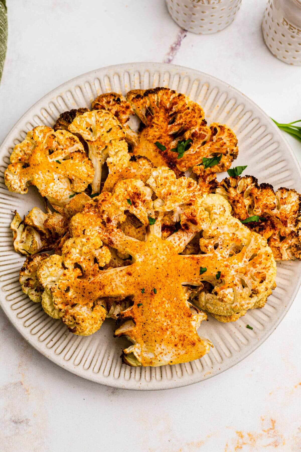 Golden cauliflower steaks on a small white plate after being cooked in the air fryer. 
