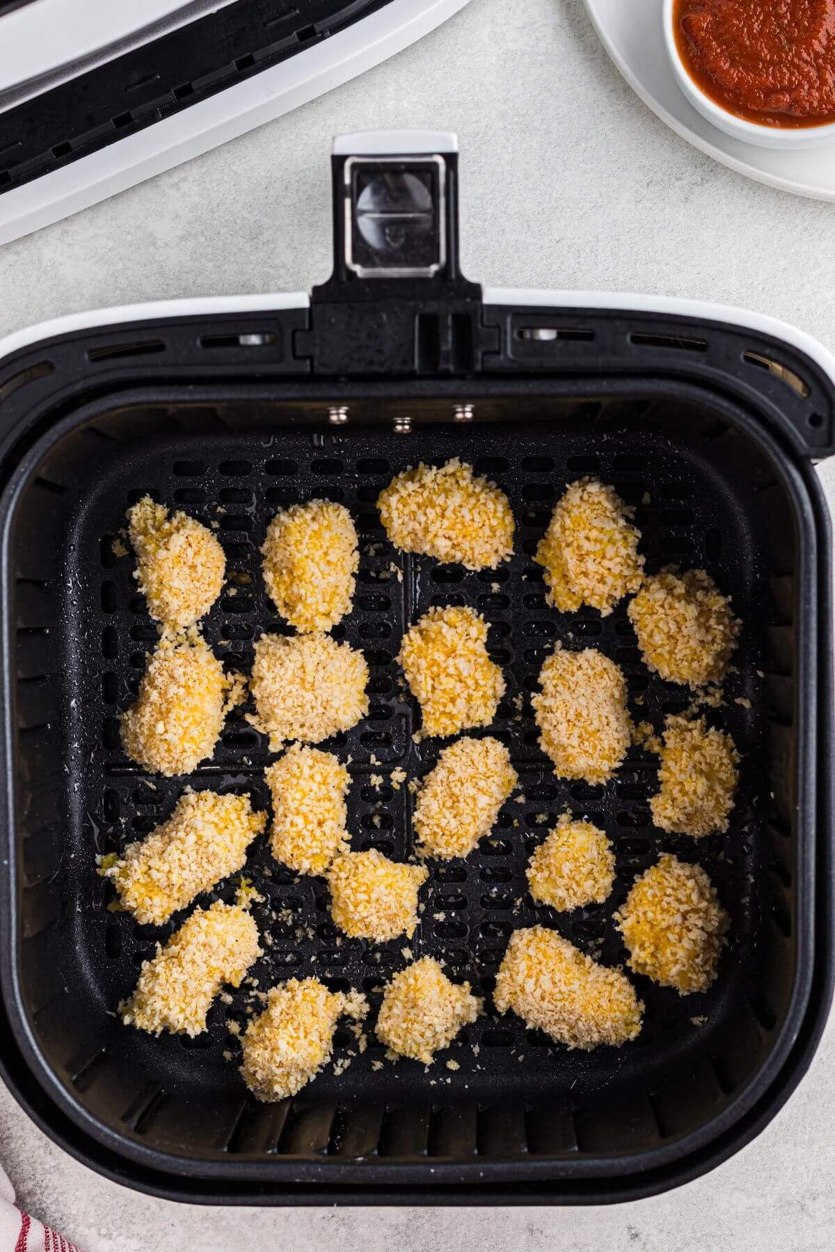 Breaded cheese curds in the air fryer basket before being cooked