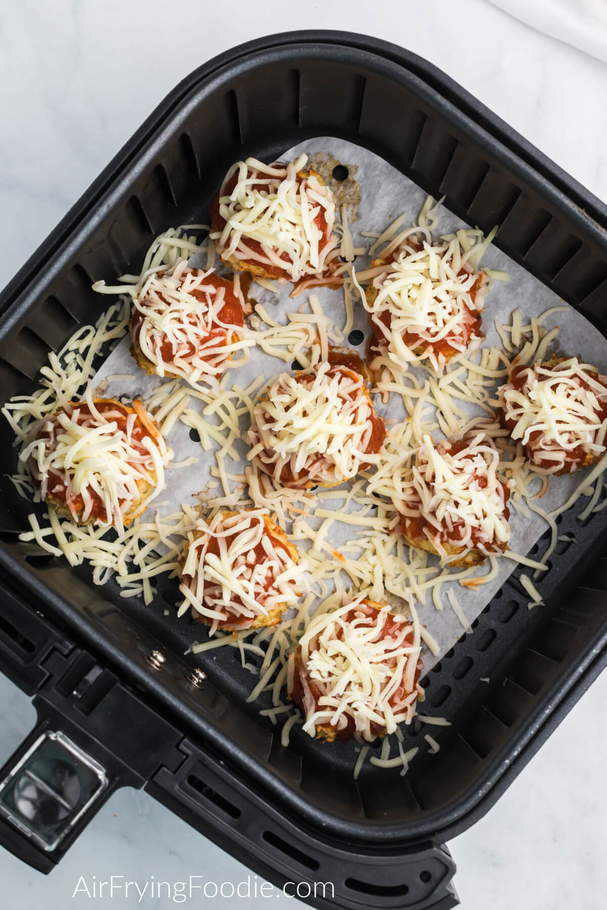 Uncooked chicken meatball in the air fryer on top of a piece of air fryer parchment paper 