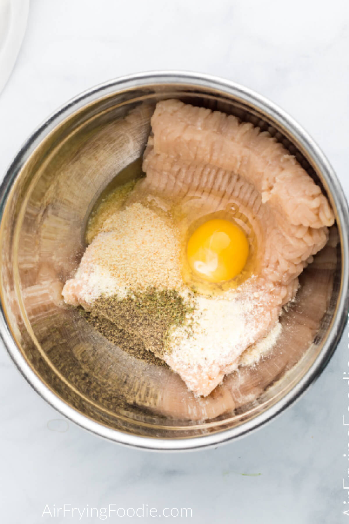 Ingredients in a large mixing bowl used to make chicken meatballs in the air fryer. 