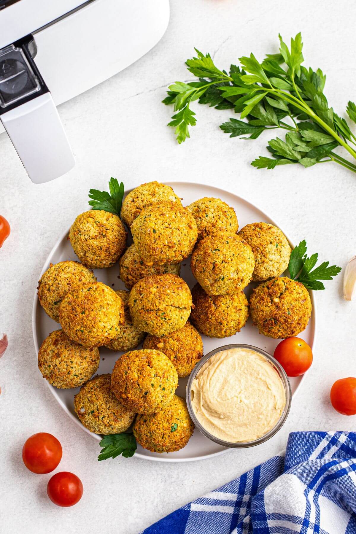 Golden brown falafels stacked on a white plate with hummus