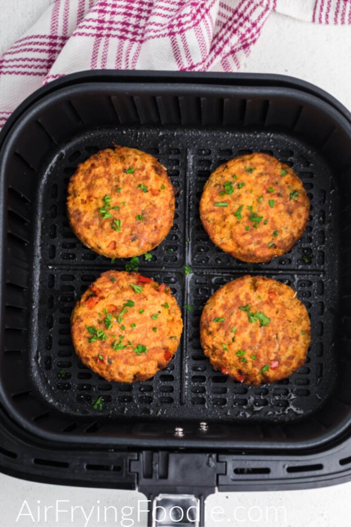 Golden orange salmon cakes in the air fryer basket after being cooked. 