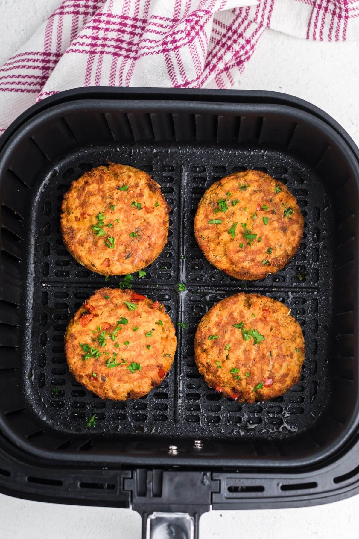 Golden brown salmon patties in the air fryer basket after being cooked. 