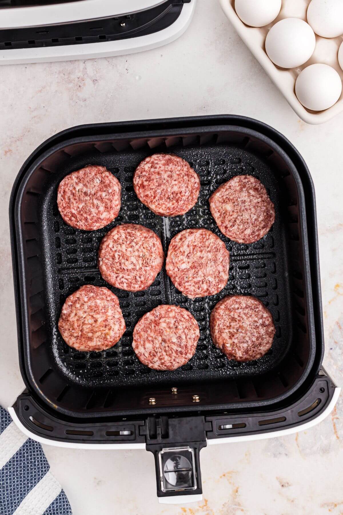 Uncooked sausage patties in the air fryer basket before being cooked. 