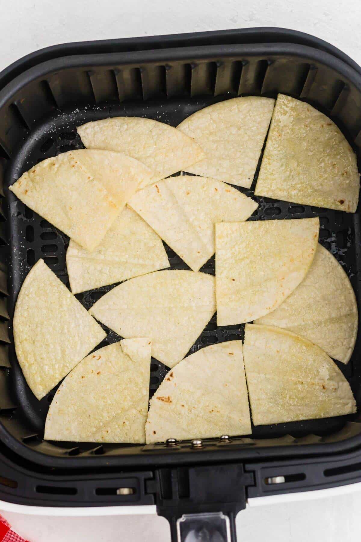 Uncooked tortillas cut into triangles, then brushed with olive oil and salt in the air fryer basket. 