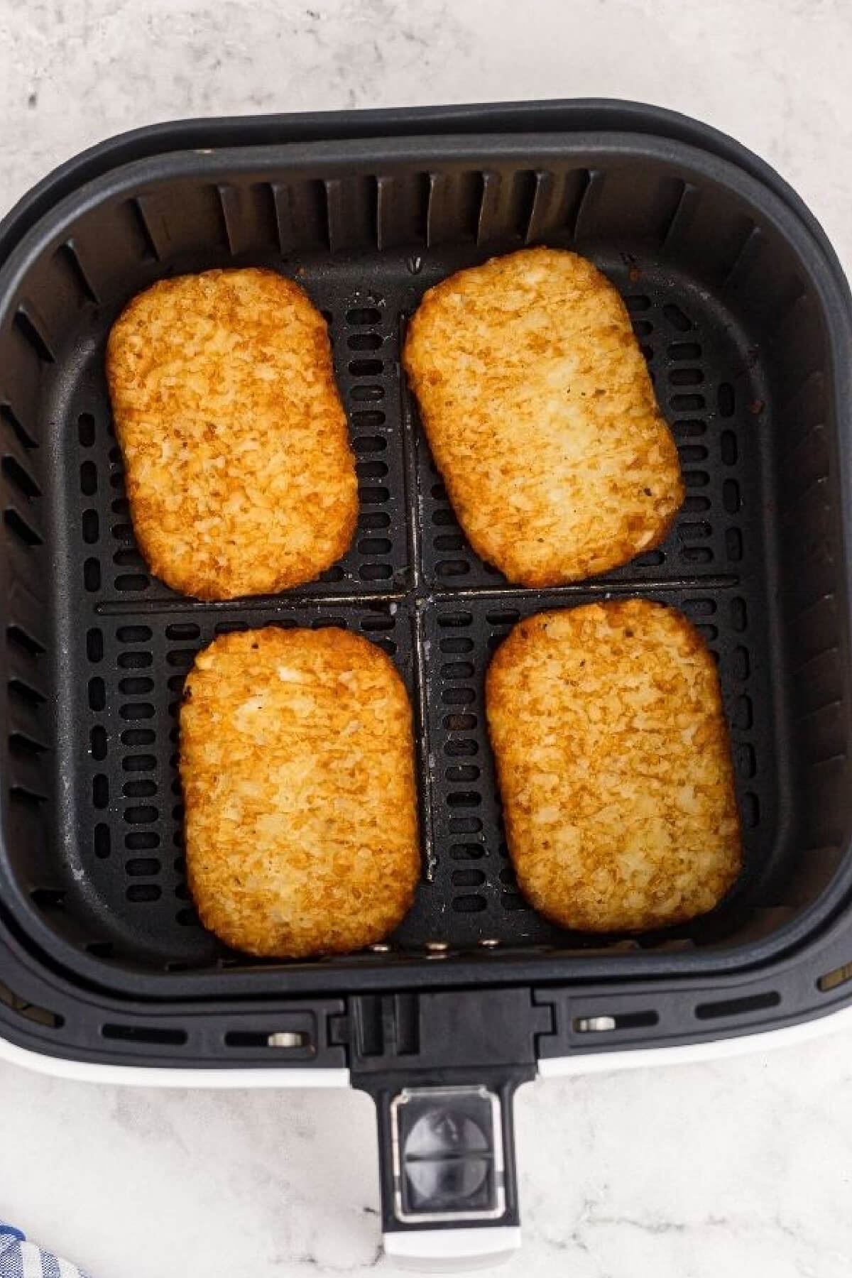 Air fried hash brown patties in the basket, ready to remove and serve.