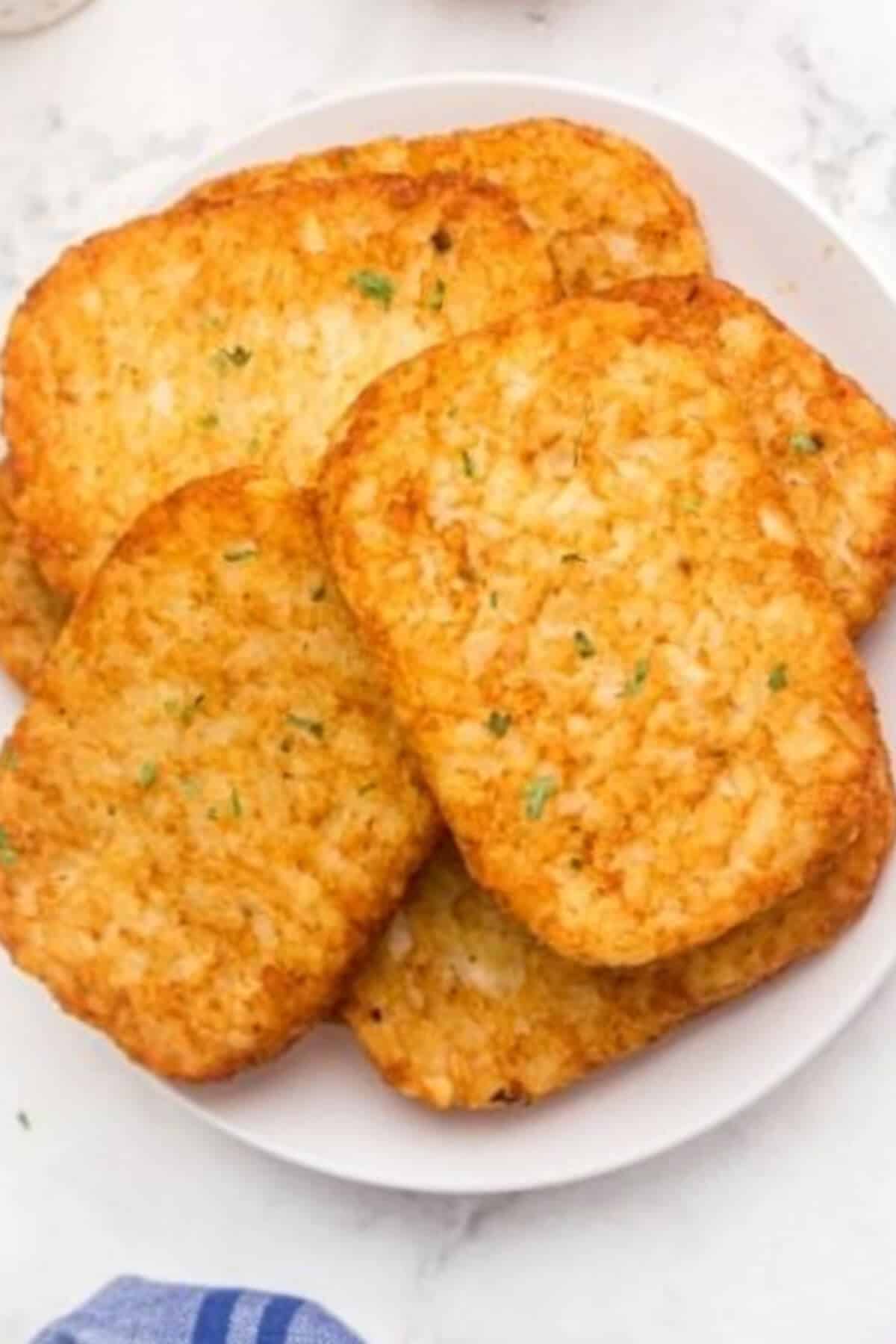 Golden hash brown patties on a small white plate. 