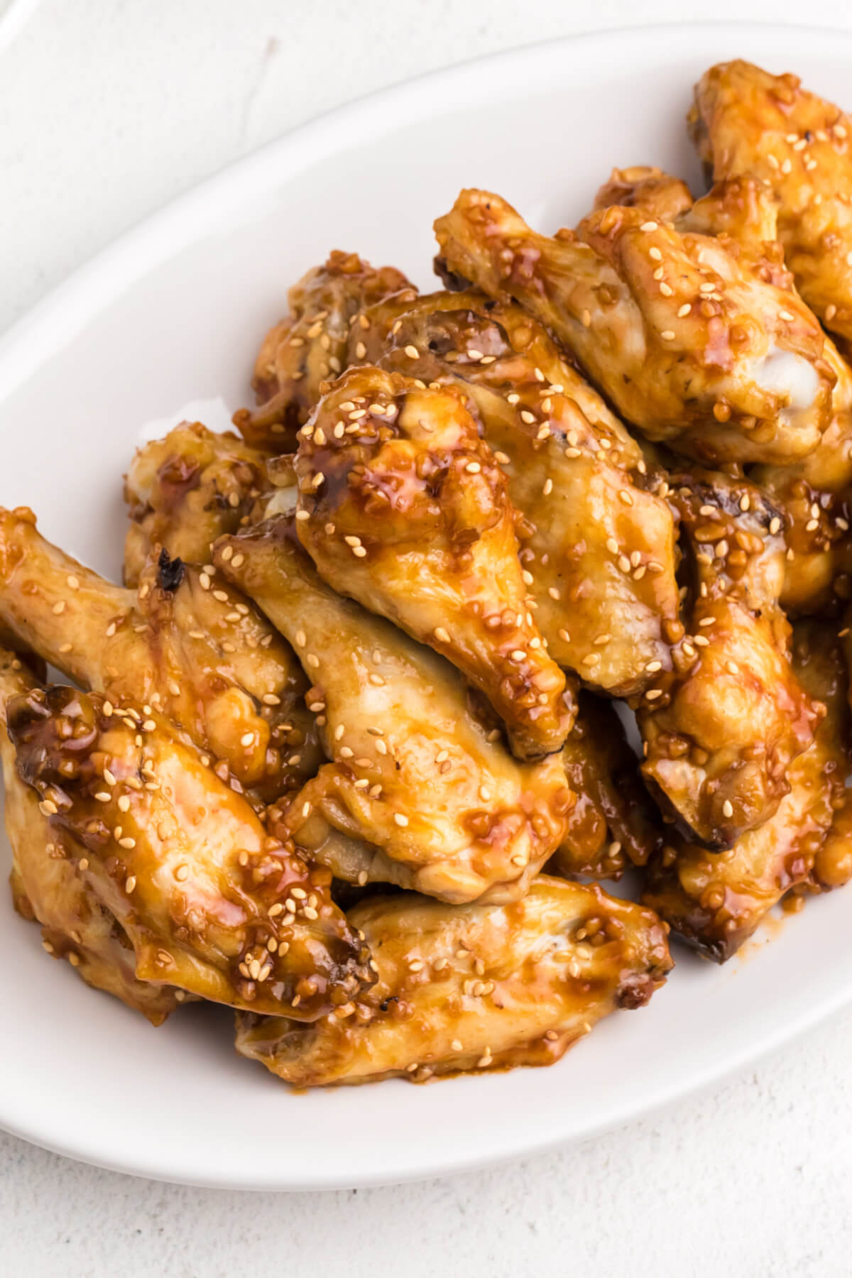 air fryer honey garlic chicken wings with sesame seeds on top, served on a white plate. 