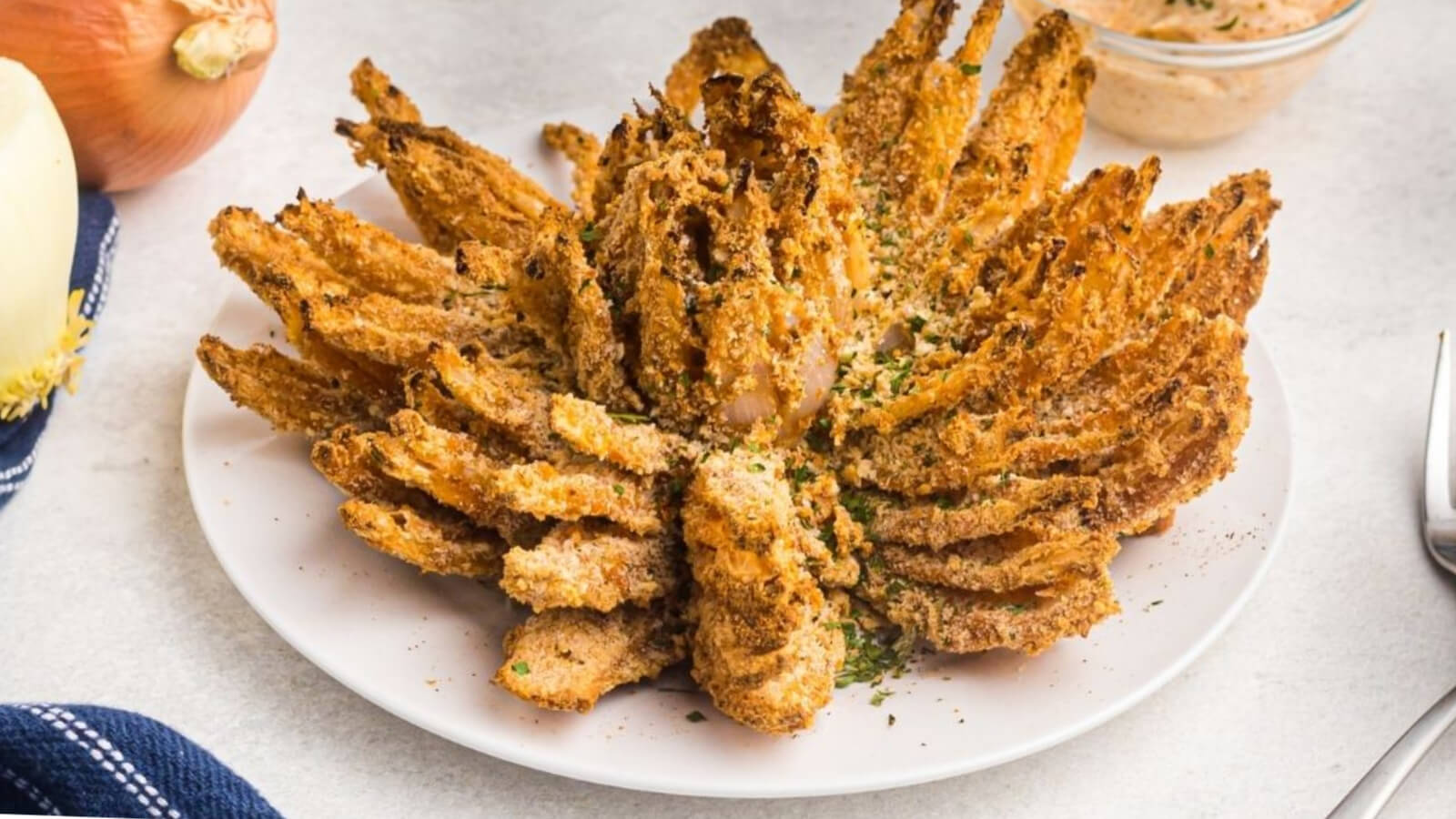 Air fryer bloomin onion on a white plate ready to serve.
