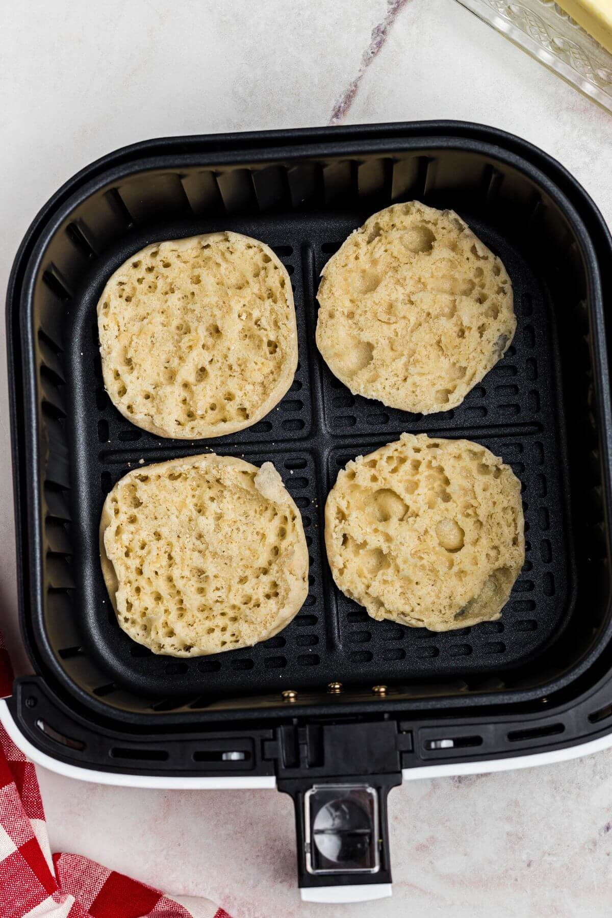 English muffins pulled apart and placed in the air fryer basket before cooking. 