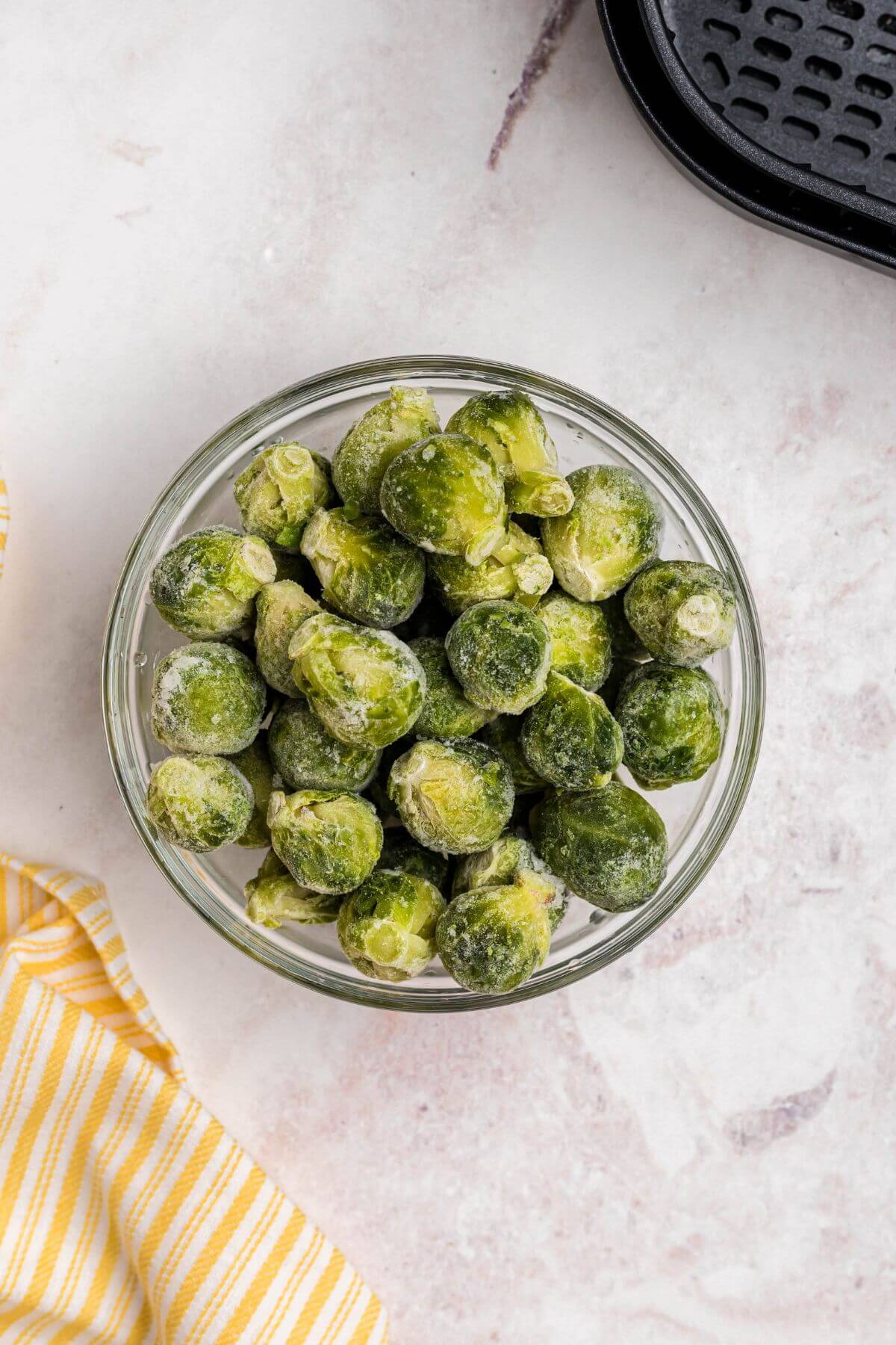 Frozen brussels sprouts in a clear glass bowl. 