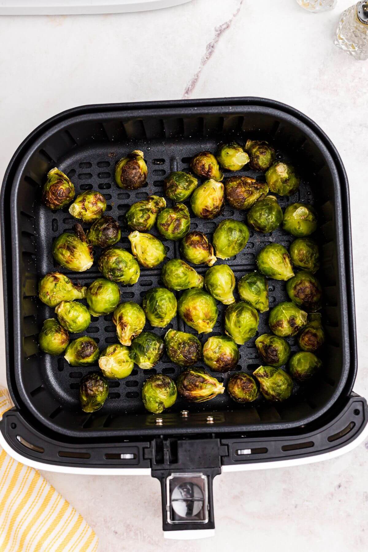 Green juicy brussels sprouts in the air fryer basket after being cooked. 