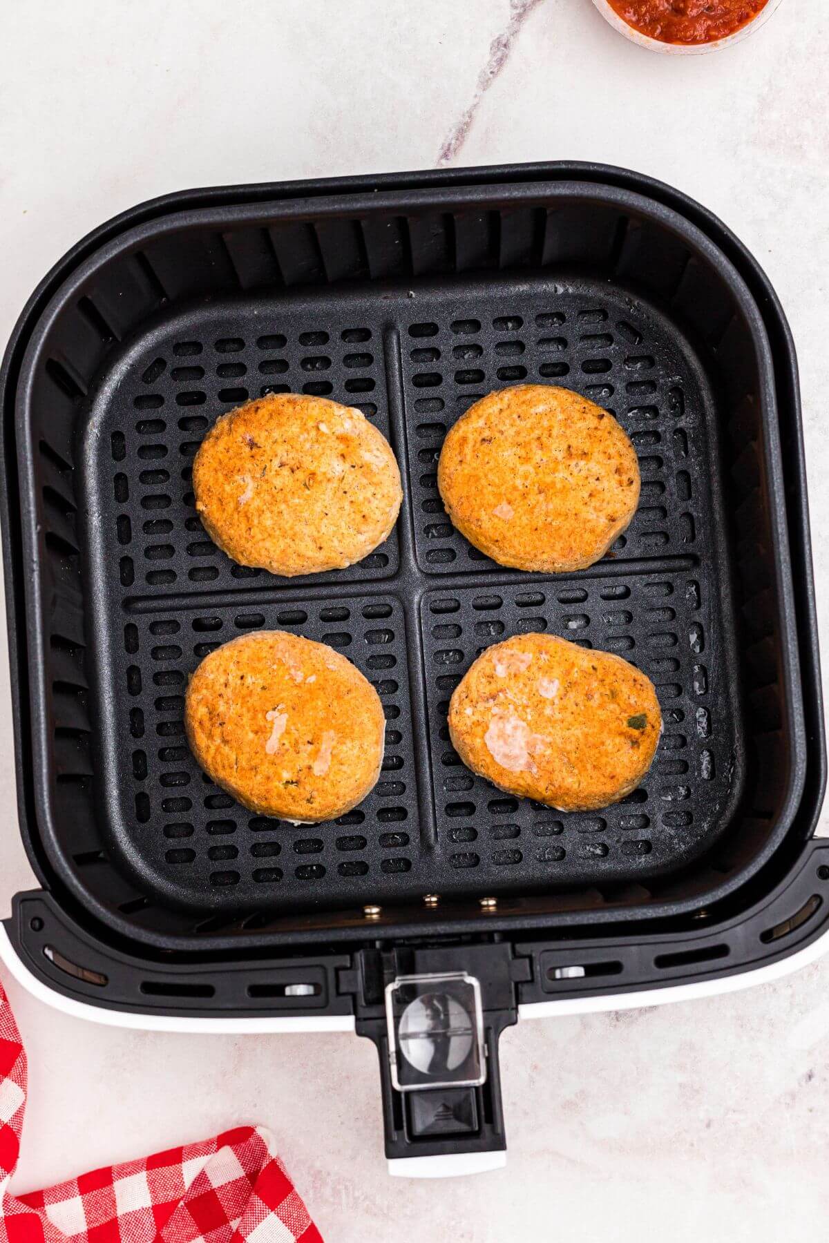 Frozen golden crab cakes in the air fryer basket before being air fried. 