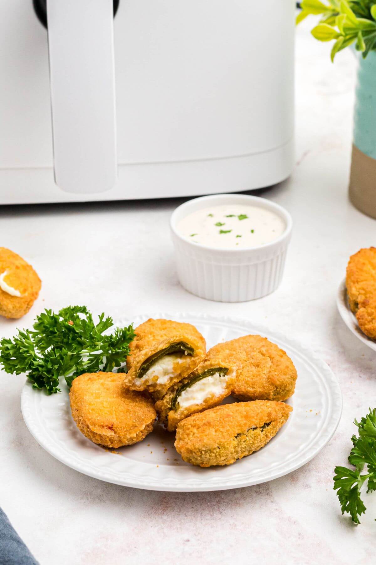 Golden crispy breaded jalapeno poppers on a small white plate. 
