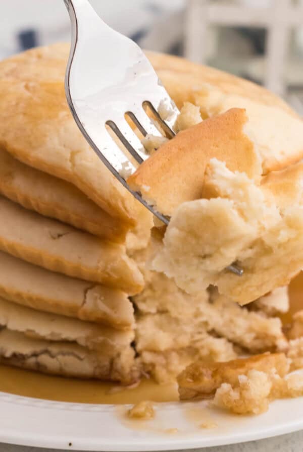 air fried pancakes stacked on a plate, topped with syrup, and a bite shot of the pancakes on a fork.