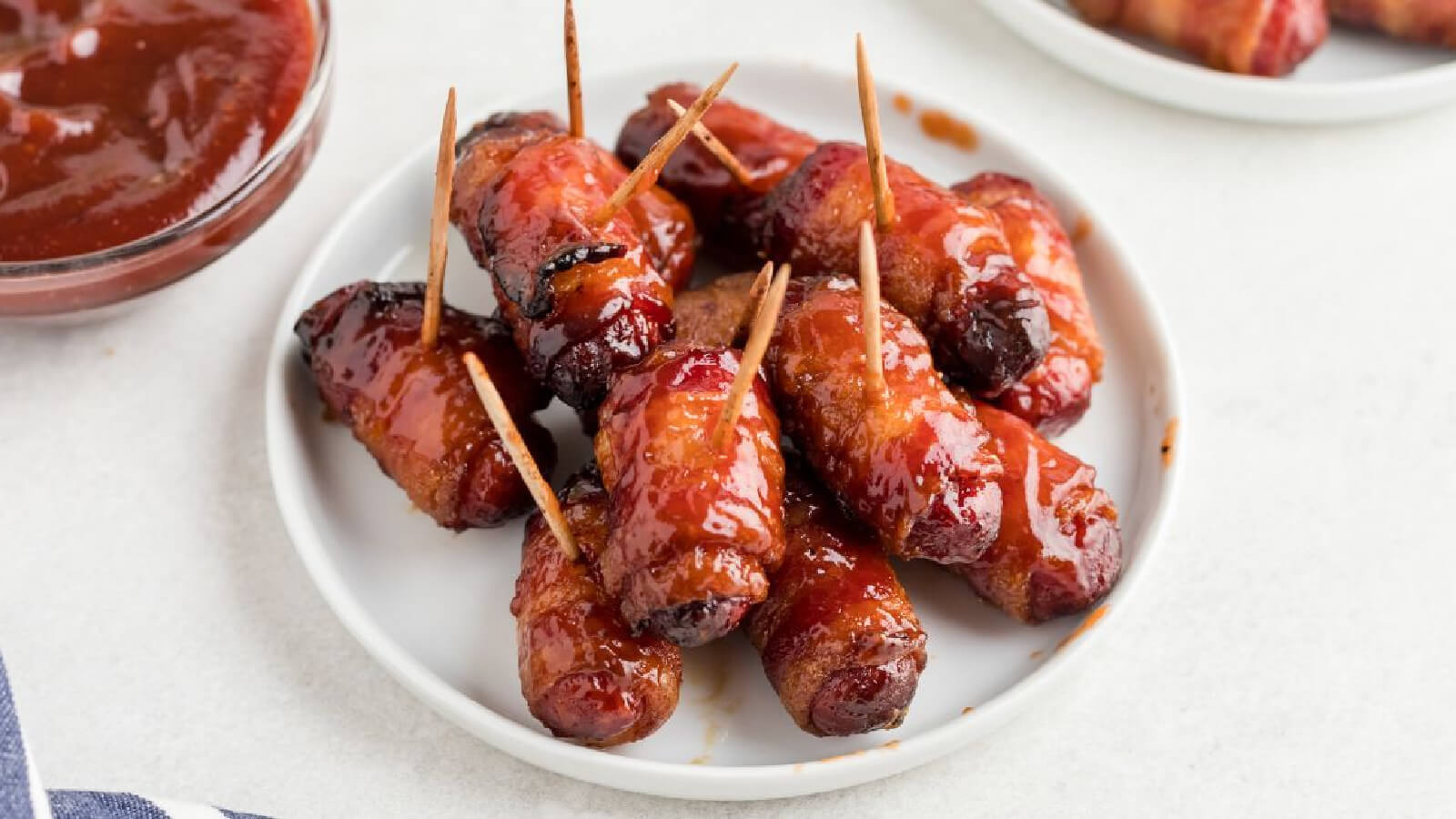 bacon wrapped smokies on a white plate, ready to serve.